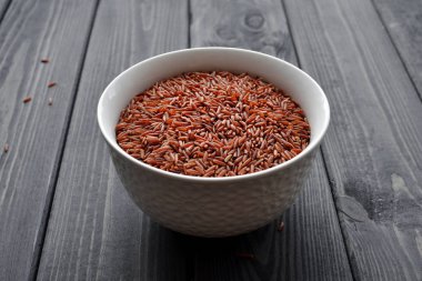 Koyu ahşap arka plan karşı seramik bir kapta Kırmızı pirinç