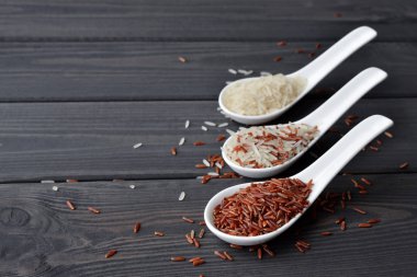 Ahşap masa arka planda kaşık pirinç farklı türleri