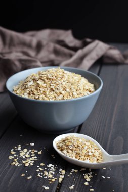 Seramik kase ve doku ile koyu ahşap masa kaşık haddelenmiş yulaf