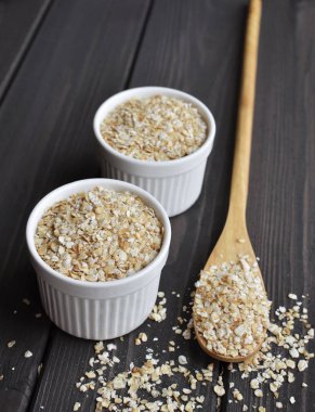 Kase ve koyu ahşap masa arka plan üzerine kaşık haddelenmiş yulaf