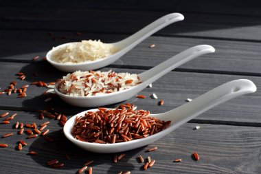 Ahşap masa arka planda kaşık pirinç farklı türleri