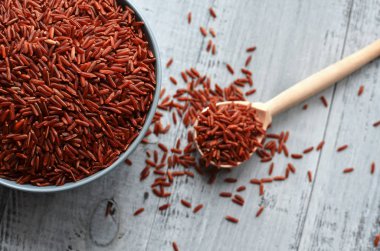 Kase ve ahşap arka plan, üstten görünüm üzerinde çiğ kırmızı pirinç ile dolu kaşık