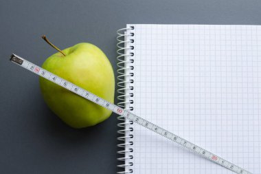 boş defter ile elma ve ölçüm bandı