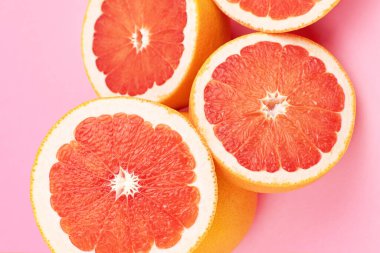 Taze bir bütün ve moda pembe kağıt arka planda greyfurt turunçgil meyvesi kesimi