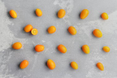 Yaratıcı düzen düzeni. Kumquat citrus meyveleri düz gri beton arka planda yatıyordu. Üst görünüm.