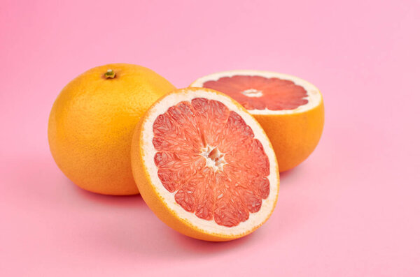 Fresh whole and cut grapefruit citrus fruits on trendy pink paper background