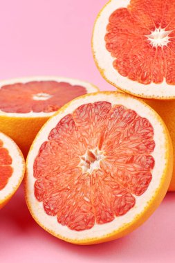 Bir yığın taze greyfurt turunçgil meyvesi ve modaya uygun pembe kağıt arka plan