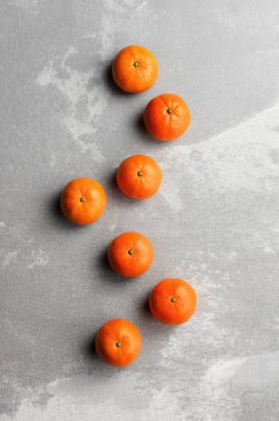 Mandarin turunçgilleri gri çimento arka planda düz sıra, üst görünüm