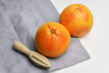 Pembe greyfurt narenciye meyvesi, ahşap el narenciyesi, beyaz masa arkaplanında keten peçeteyle sıkma.