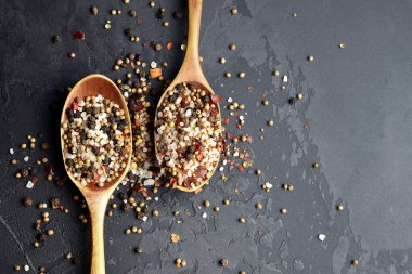 Koyu taşlı arka planda iki büyük tahta kaşıkta çeşitli baharatlar. Yemek pişirme konsepti. Üst görünüm, alanı kopyala