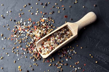 Koyu taşlı arka planda çeşitli baharatlar ahşap kepçeyle karıştırılır. Yemek pişirme konsepti. Üst görünüm