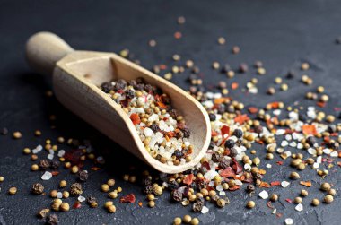 Koyu arkaplandaki ahşap kepçeyle farklı baharatların karışımı. Biberler, deniz tuzu, kardamon, hardal tohumu ve kırmızı biber taneleri. Yemek malzemeleri fotoğrafçılığı