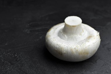 Şampiyon mantarı siyah taş arka planda. Vegan gıda konsepti. Yan görünüm, boşluk kopyala.