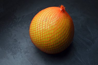 Koyu gri grunge arka planda koruyucu ağa sarılı Pomelo meyvesi