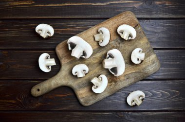 Koyu ahşap arka planda yeni kesilmiş şampiyonlar. Yemek hazırlama konsepti. Üst görünüm.