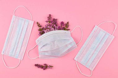Pembe arka planda leylak çiçekli koruyucu yüz maskeleri. Cteative düz yatıyordu.