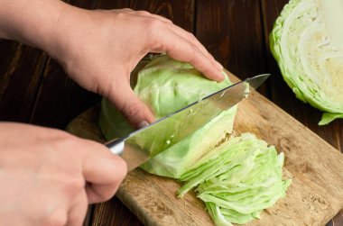 Beyaz lahana salatası doğruyorum. Elleri bıçaklı tahta kesme tahtasıyla.