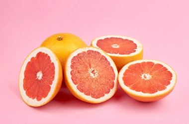 Bir sürü greyfurt narenciye, pembe arka planda.