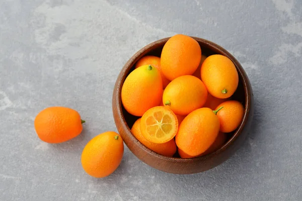 Agrumes kumquat fruits dans un bol en bois. Nourriture végétalienne saine. Kumquat fruits coupés en deux. Vue du dessus. — Photo