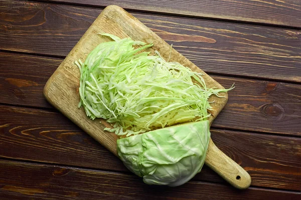 Wooden cutting board with chopped cabbage salad. — Stock Photo, Image