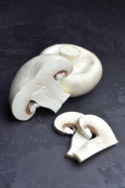 Siyah arkaplanda çiğ şampiyon mantarları. Vejetaryen yemek pişirme kavramı.