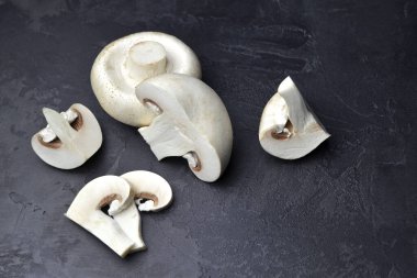 Siyah arkaplanda çiğ şampiyon mantarları. Vejetaryen yemek pişirme kavramı.