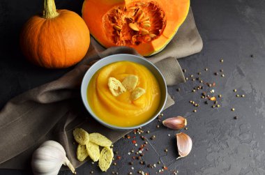 Seramik bir kasede balkabağı çorbası. Taze balkabağı, sarımsak, buğday ekmeği ve arkaplanda keten kumaştan arkaplan, grunge koyu masa baharatları.