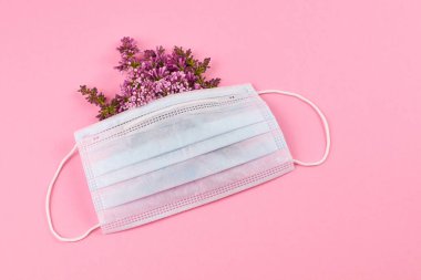 Pembe arka planda çiçekli tıbbi yüz maskesi. Üst görünüm, alanı kopyala.