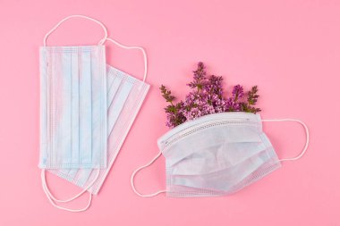 Pembe arka planda çiçekli tıbbi koruyucu yüz maskesi. Bahar alerjisi konsepti. Yaratıcı düz yatak.