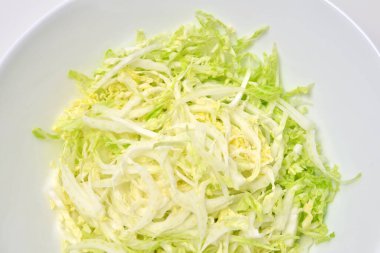 Beyaz arka planda Çin lahana salatası. Vejetaryen gıda konsepti.