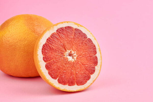 Fresh pink grapefruit citrus fruits on pink background, copy space