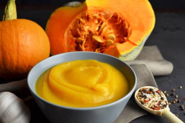 Taze balkabağı, sarımsak, kıtır ekmek ve arkaplanda keten kumaşlı grunge siyah arkaplan baharatlı balkabağı çorbası.