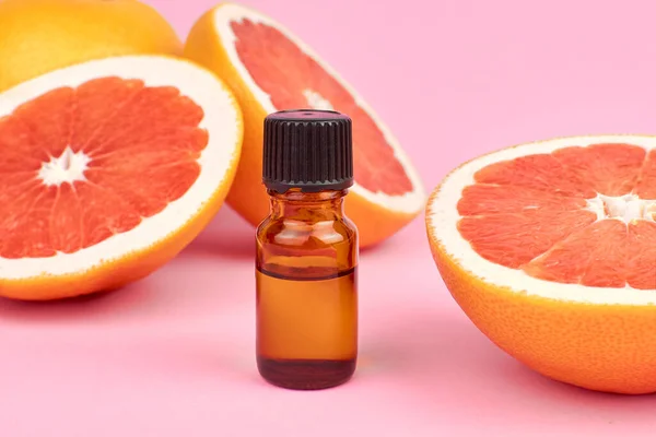Citrus grapefruit essential oil, aromatherapy or natural organic cosmetic on pink background. Natural body and skin treatment.