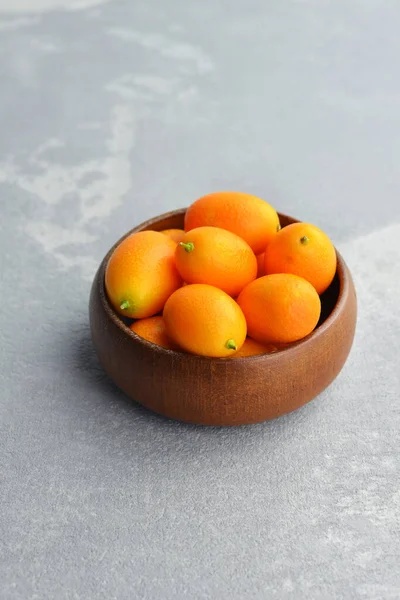 Tál tele friss kumquat gyümölcs szürke beton háttér — Stock Fotó
