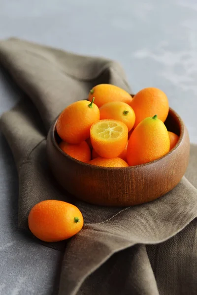 Friss kumquat gyümölcsök fából készült tálban, vászon alapon. Egészséges vegán ételek. — Stock Fotó