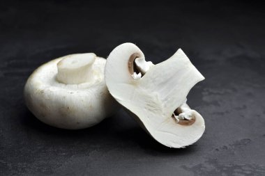 Şampiyon mantarları, tam ve yarım, siyah arkaplan. Vejetaryen gıda konsepti.