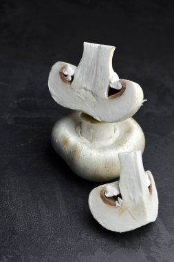 Taze dilimlenmiş şampiyon mantarları. Koyu arkaplanda, pişirmeye hazır..