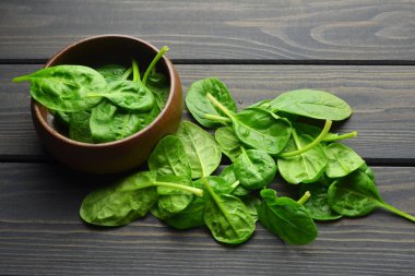Taze ıspanak yaprakları koyu ahşap kasede koyu kırsal arka planda. Sağlıklı vejetaryen gıda konsepti. Çevreye duyarlı vejetaryen yaşam tarzı.