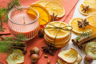 Kuru portakal ve elma dilimleri aroma mumu, baharatlar, fındık ve ardıç dalı, noel zamanı kompozisyonu