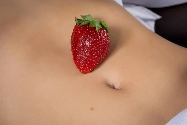 Red  strawberries in the stomach of a young girl.