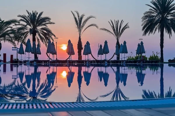 Sunrise over the sea, palm trees and swimming pool. City Of Kemer, Turkey