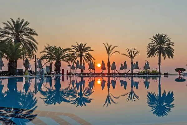 Deniz, palmiye ağaçları ve yüzme havuzu güneş doğuyor. Kemer City, Türkiye