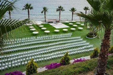 Beyaz sandalye ve masalar ile yeşil bir alan. Düğün törenleri için yer.