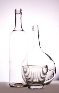 Beyaz arka planda farklı boyutta iki cam berrak şişe.