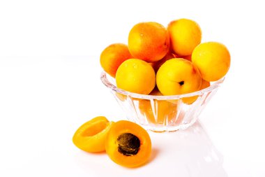 Su damlacıkları ve bir kemik ile kesilmiş bir kayısı ile cam bir tabak üzerinde olgun ve parlak kayısı.