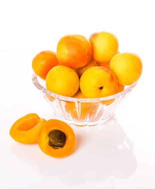 Su damlacıkları ve bir kemik ile kesilmiş bir kayısı ile cam bir tabak üzerinde olgun ve parlak kayısı.