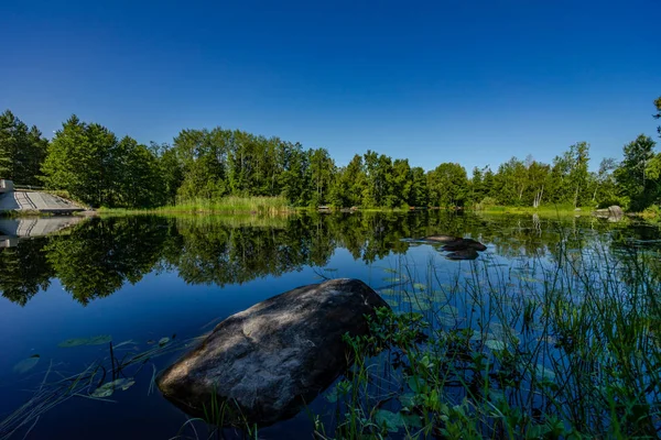 Rus doğasının hoş manzarası. Bulutlar gölde, kıyılarda yeşil ağaçlar ve beyaz huş ağaçları yansıyor..