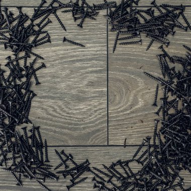 Ahşap arka planda siyah vida lı çivi yığını. Masadaki bir sürü vida.