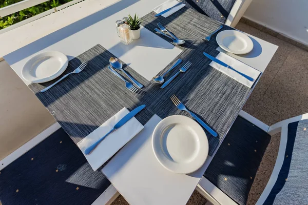 Table set with dishes for dinner on the veranda. The table is set with dishes and Cutlery for dinner on the veranda.