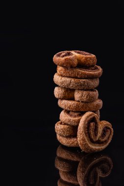 Kurabiyeler toz şekerli kalp şeklinde. Lezzetli, taze kurabiyeler siyah arka planda bir sütuna istiflenir. Tatlı nefis..